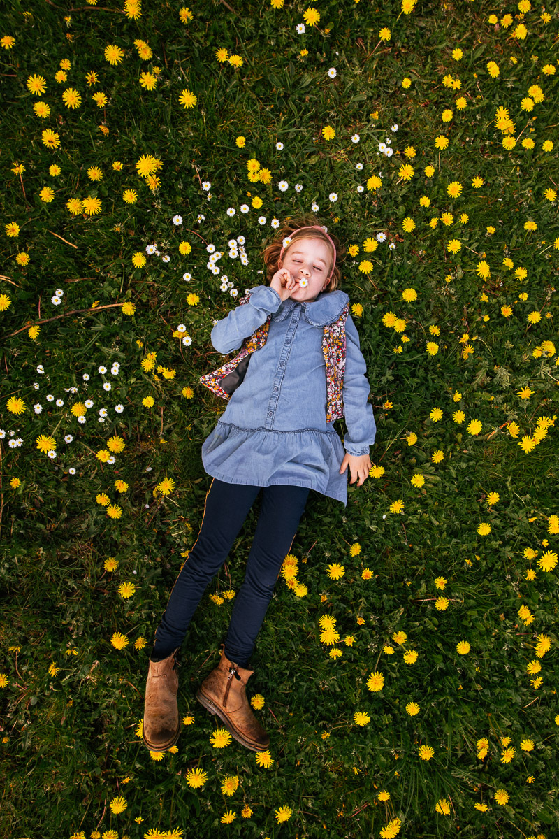 Kind ligt in bloemenveld tijdens fotoshoot