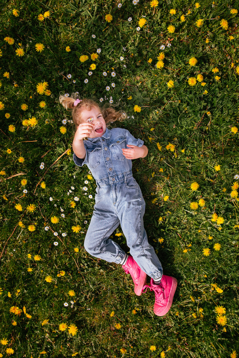 Kind ligt in bloemenveld tijdens fotoshoot